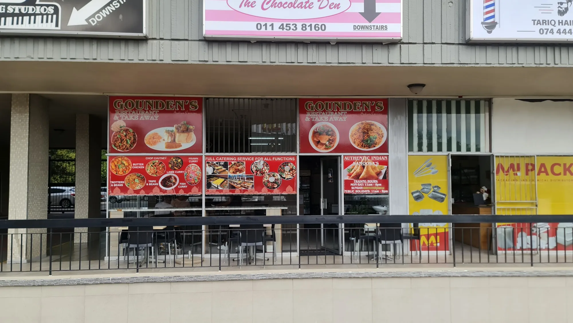 Printed shopfront signage panels above a restaurant, showing food photography and menu items.