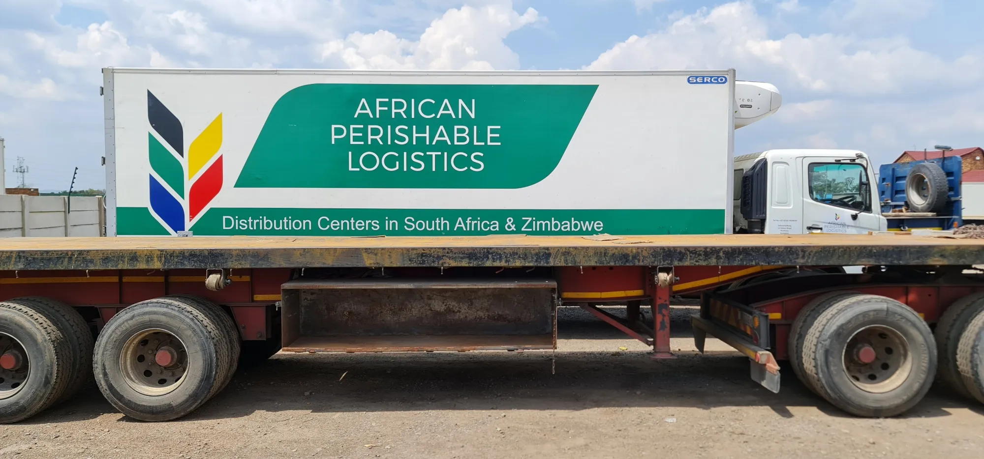 Side of a refrigerated truck body finished in full-colour vehicle branding with a large logo and lettering.